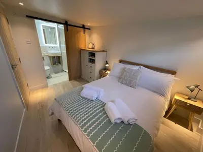 a bedroom with a bed with towels on it at Self contained double bedroom with ensuite, private entrance, free parking , 5 min walk to beach in St Ives