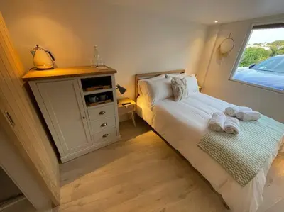 a bedroom with a bed with towels on it at Self contained double bedroom with ensuite, private entrance, free parking , 5 min walk to beach in St Ives