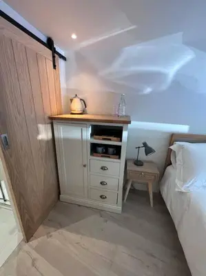 a bedroom with a white cabinet next to a bed at Self contained double bedroom with ensuite, private entrance, free parking , 5 min walk to beach in St Ives