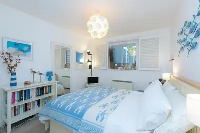 a white bedroom with a bed and a chandelier at 13 Carrack Widden with complimentary spa passes in St Ives