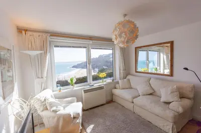 a living room with a couch and a large window at 13 Carrack Widden with complimentary spa passes in St Ives