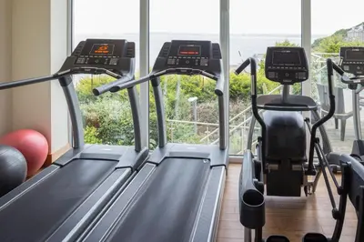 a gym with two treadmill machines and a window at 13 Carrack Widden with complimentary spa passes in St Ives