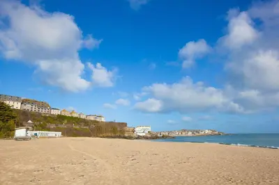 a sandy beach with buildings on a hill next to the ocean at 13 Carrack Widden with complimentary spa passes in St Ives