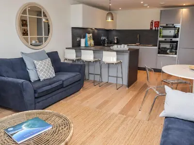 a living room with a blue couch and a kitchen at Bamaluz in Carbis Bay