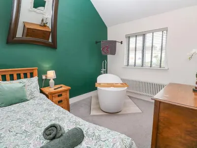 a bedroom with a bed and a bath tub and a sink at Cinders Loft in Redruth