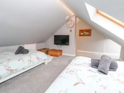 two beds in a attic room with a tv at Cinders Loft in Redruth