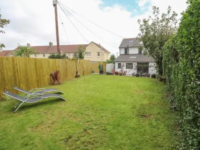 a backyard with a fence and a bench in the grass at Cinders Loft in Redruth