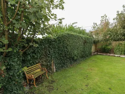 a park bench sitting in a yard next to a hedge at Cinders Loft in Redruth