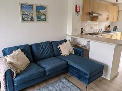 a blue couch in a living room with a kitchen at No.7 Perran View in St. Agnes
