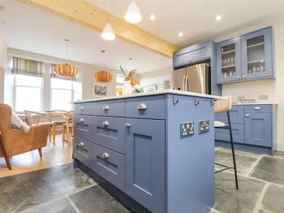a kitchen with blue cabinets and a dining room at Treveddoe Farmhouse in Bodmin