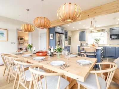 a kitchen and dining room with a wooden table and chairs at Treveddoe Farmhouse in Bodmin