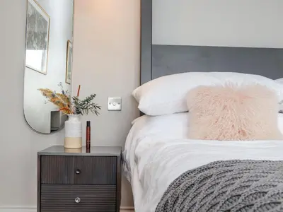 a bedroom with a bed with a mirror and a nightstand at Treveddoe Farmhouse in Bodmin