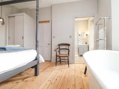 a bedroom with a bed and a chair at Treveddoe Farmhouse in Bodmin