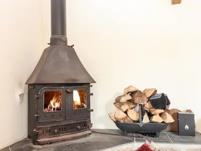 a woodburning stove with a bowl of logs at The Barley Crush in Bodmin