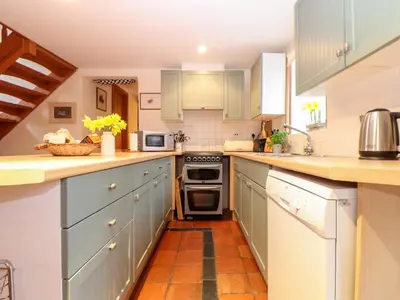 a kitchen with blue cabinets and an orange tile floor at The Barley Crush in Bodmin