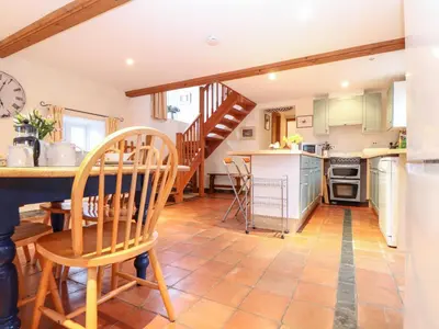 a kitchen with a table and chairs and a staircase at The Barley Crush in Bodmin