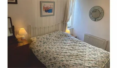 a bedroom with a bed and a lamp and a mirror at The Sail Loft in Lostwithiel