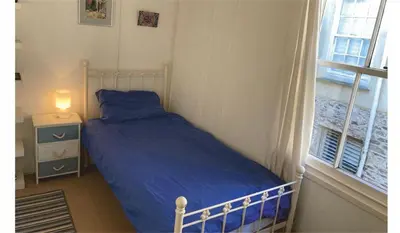 a bedroom with a bed with a blue comforter and a window at The Sail Loft in Lostwithiel