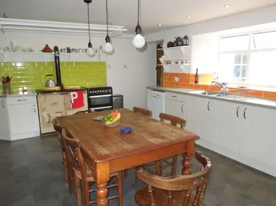 a kitchen with a wooden table and some chairs at Hallagather Self Catering in Bude