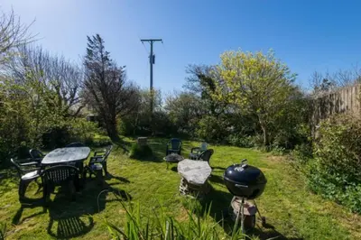 a grill and tables and chairs in a yard at Hallagather Self Catering in Bude