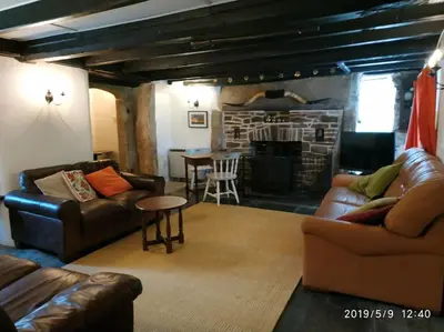 a living room with couches and a table and a fireplace at Hallagather Self Catering in Bude