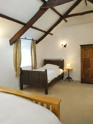 a bedroom with two beds in a room with beams at Hallagather Self Catering in Bude