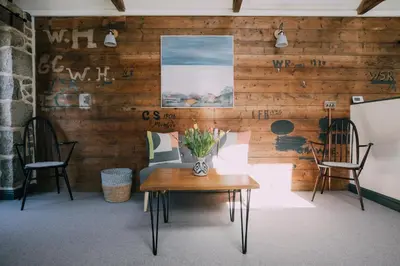 a room with wooden walls and a table and two chairs at The Old Workshop in St Ives