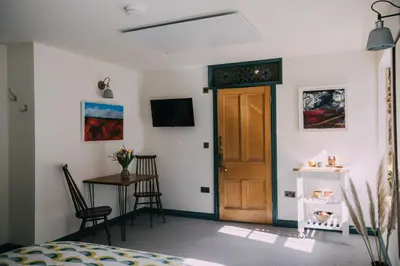 a bedroom with a door and a table and chairs at The Old Workshop in St Ives