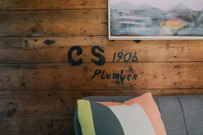 a sign on a wooden wall with a couch at The Old Workshop in St Ives
