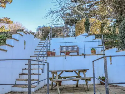 a picnic table and stairs with a bench next to a wall at Rosemount in Marazion