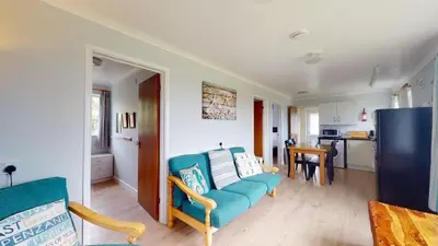 a living room with a blue couch and a kitchen at D57 Bramble, Riviere Towans in Hayle