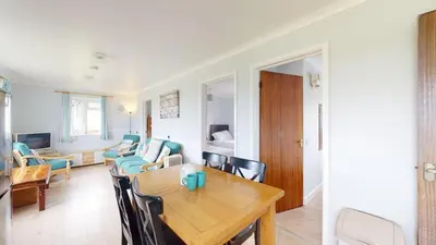 a dining room and living room with a table and chairs at D57 Bramble, Riviere Towans in Hayle