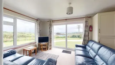 a living room with a couch and a large window at D58 Penlee, Riviere Towans in Hayle