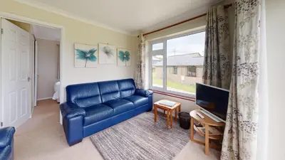 a living room with a blue couch and a window at D58 Penlee, Riviere Towans in Hayle