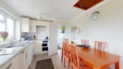 a kitchen with a wooden table and a dining room at D58 Penlee, Riviere Towans in Hayle