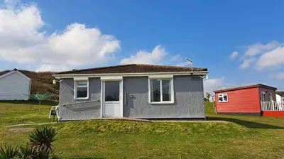 a small house with a red door in a yard at E14 Sea Haven, Riviere Towans in Hayle