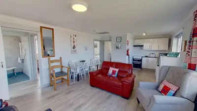 a living room with a red couch and a kitchen at E14 Sea Haven, Riviere Towans in Hayle
