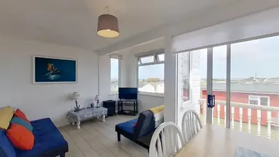 a living room with a blue couch and a window at E20 The Firs, Riviere Towans in Hayle