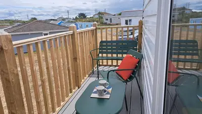 a balcony with two chairs and a table with a book on it at E20 The Firs, Riviere Towans in Hayle