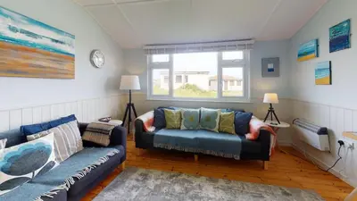 a living room with a couch and a chair at E23 Porthpean, Riviere Towans in Hayle