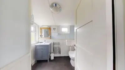 a white bathroom with a sink and a toilet at E23 Porthpean, Riviere Towans in Hayle