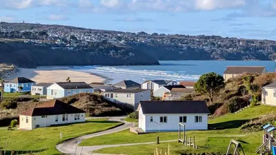 a row of houses on a hill next to the ocean at E29 Bonnie Bank, Riviere Towans in Hayle