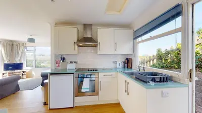 a kitchen with white cabinets and a large window at E28 HI-Up, Riviere Towans in Hayle