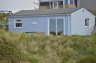 a blue house sitting on top of a hill at E30 Lant View, Riviere Towans in Hayle