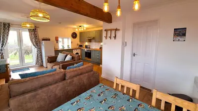 a living room with a couch and a kitchen at E39 Craigmore, Riviere Towans in Hayle
