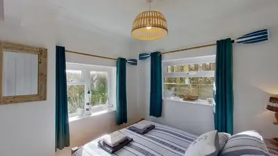 a bedroom with blue curtains and a bed and a window at E39 Craigmore, Riviere Towans in Hayle