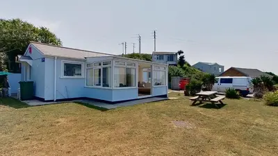 a small blue house with a picnic table in a yard at E37 Blue Haze, Riviere Towans in Hayle