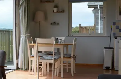 a dining room with a table and chairs and a window at E46 Dunroven, Riviere Towans in Hayle