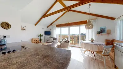 a kitchen and living room with a table and chairs at E48 Redville, Riviere Towans in Hayle