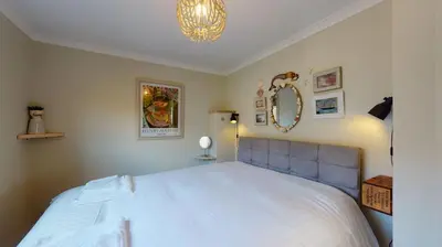 a bedroom with a large white bed and a chandelier at E48 Redville, Riviere Towans in Hayle